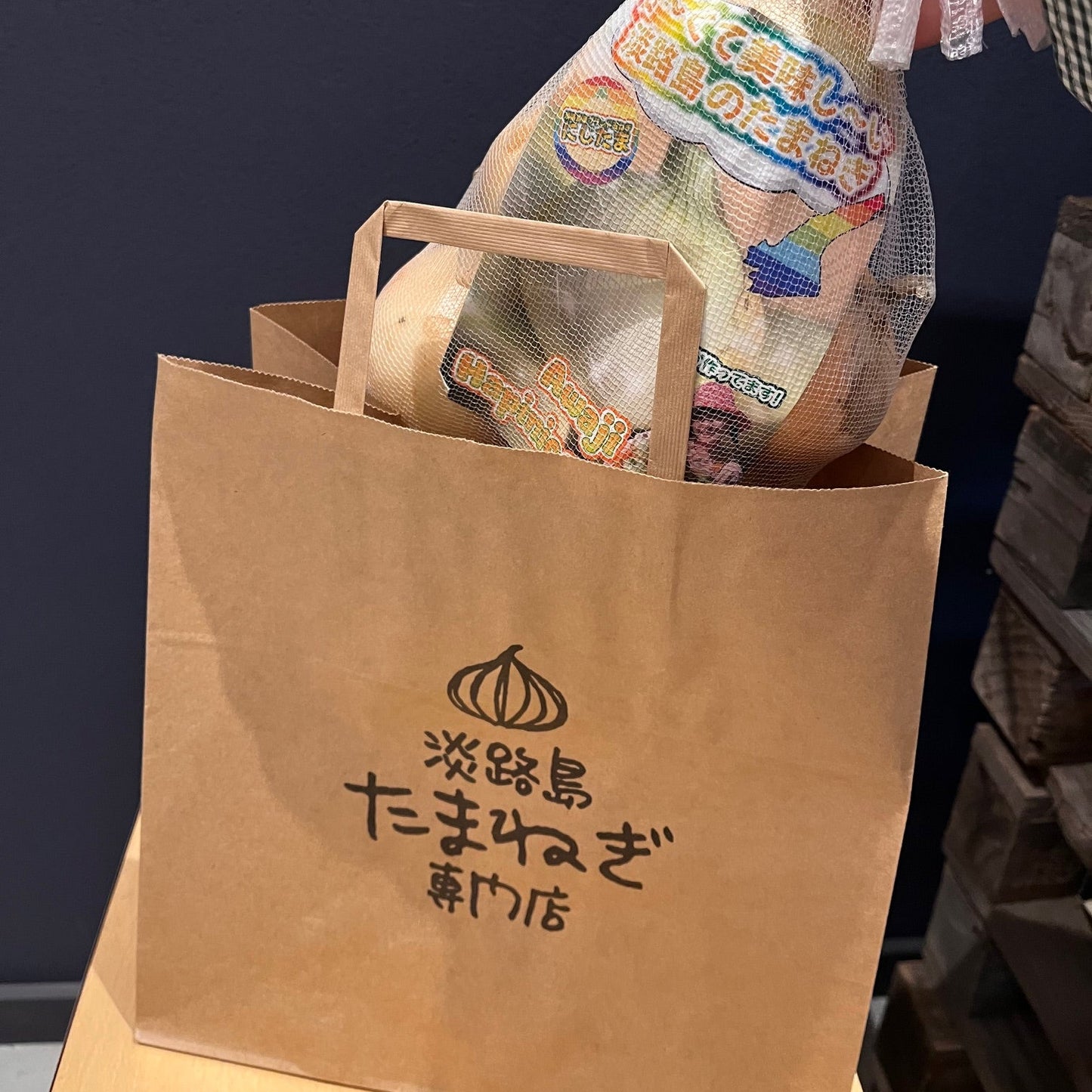 淡路島玉ねぎ専門店の買い物袋に大きさの比較に玉ねぎ一キログラムいれている