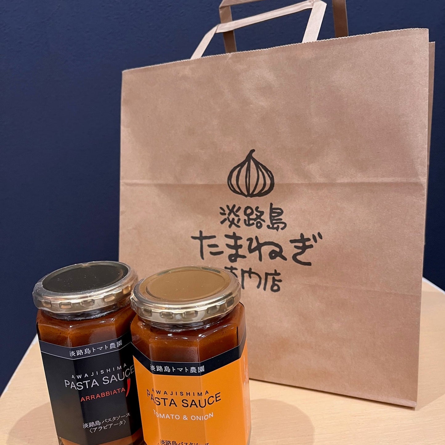 淡路島玉ねぎ専門店の買い物袋に大きさの比較にパスタソースを2個並べている