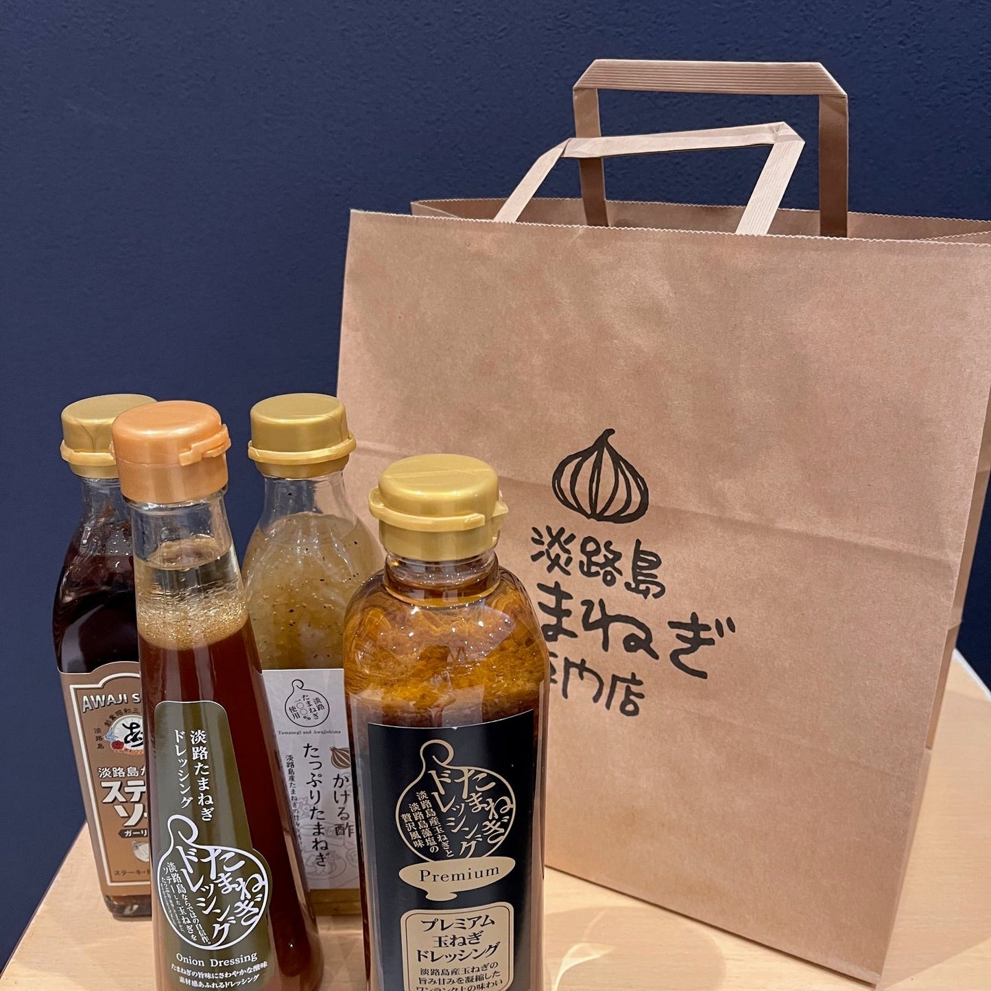 淡路島玉ねぎ専門店の買い物袋に大きさの見本のドレッシング4本並べて