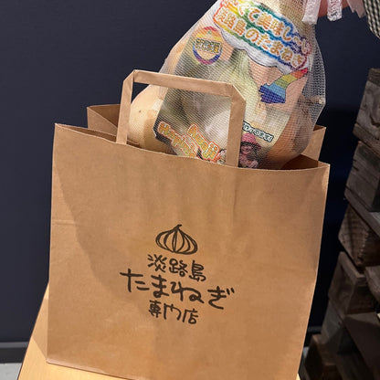 淡路島玉ねぎ専門店の買い物袋に大きさの比較に玉ねぎ一キログラムいれている